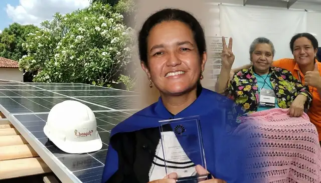 Laura recebendo um prêmio ao lado da equipe da Jugaad, com painéis solares ao fundo.